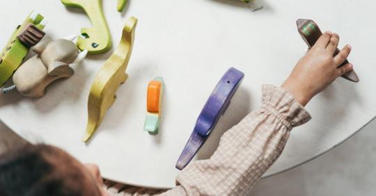 Otrok se igra s pisanimi lesenimi igračami v igrivem notranjem okolju